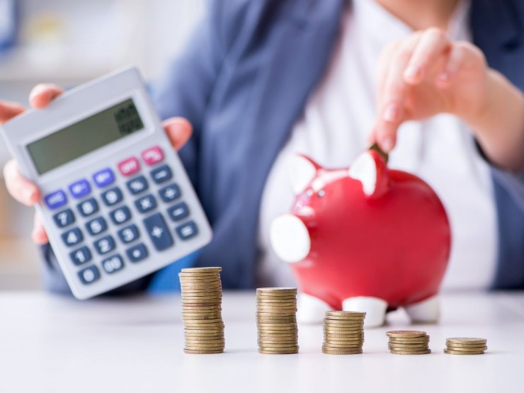 calcolatrice, monete e salvadanaio a forma di porcellino