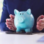 mani che proteggono un salvadanaio a forma di porcellino azzurro