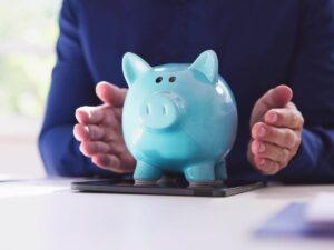 mani che proteggono un salvadanaio a forma di porcellino azzurro