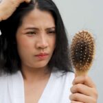 donna che si tocca testa e con spazzola