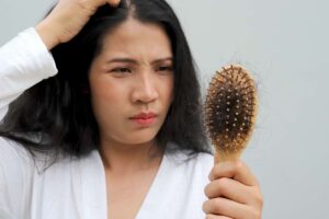 donna che si tocca testa e con spazzola