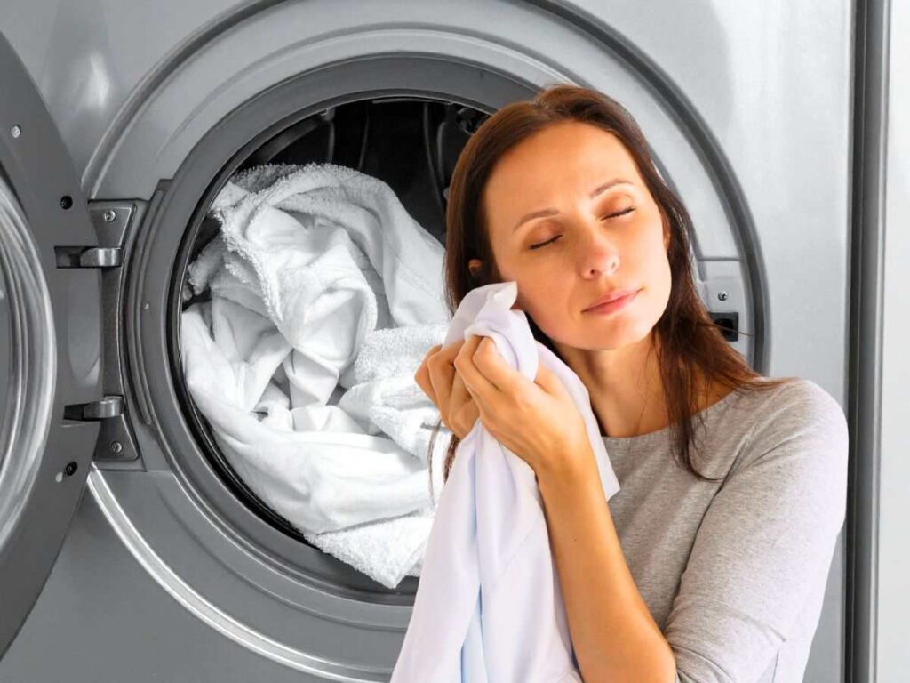 sfondo asciugatrice in azione e donna che odora panni puliti