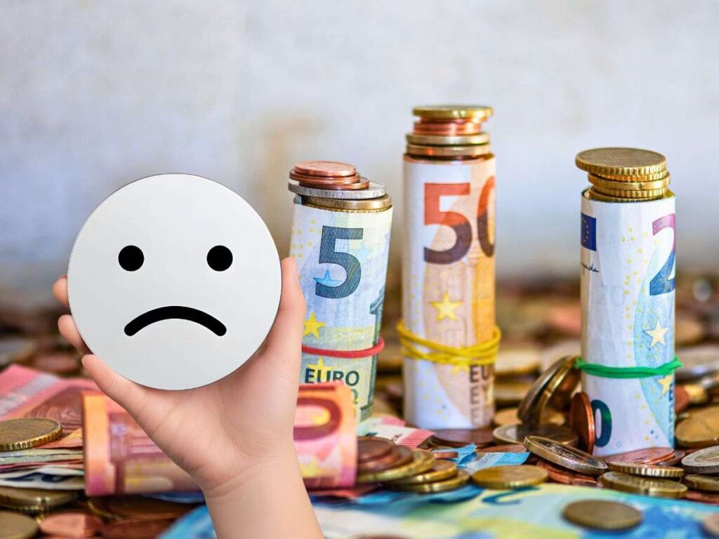 sfondo banconote e monete euro e mano con sagoma faccina triste