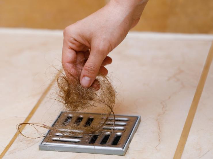 mano preleva capelli da scarico doccia