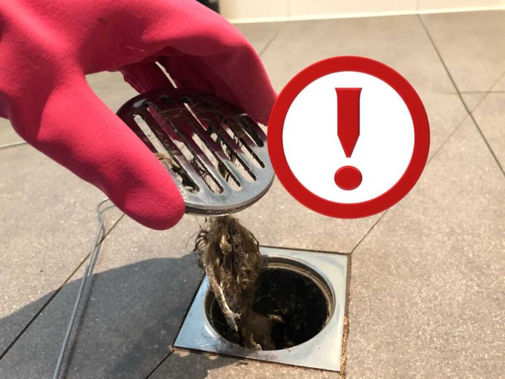 capelli nello scarico della doccia, guanto rosso e punto esclamativo