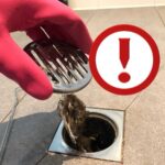 capelli nello scarico della doccia, guanto rosso e punto esclamativo