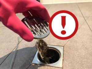 capelli nello scarico della doccia, guanto rosso e punto esclamativo