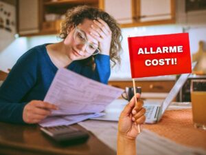 sfondo donna legge bollette altissime e bandiera in mano con scritta allarme costi