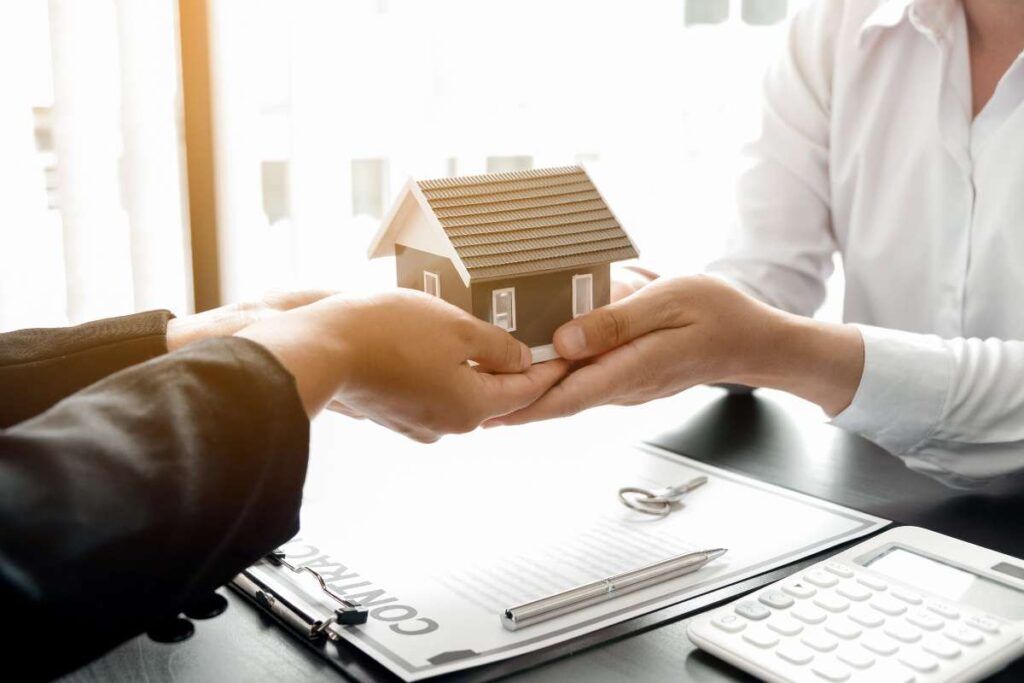 quattro mani con modellino casa