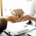 quattro mani con modellino casa